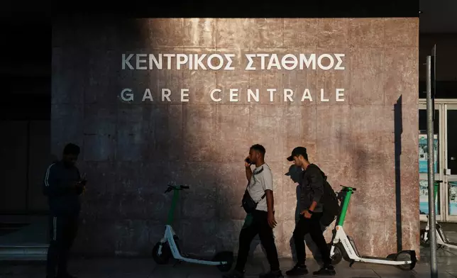 People walk outside the closed main railway station during a nationwide 24-hour strike, as labor demand higher wages and the withdrawal of a bill that changes work hours in Athens, Greece, Wednesday, Oct. 1, 2025. (AP Photo/Thanassis Stavrakis)