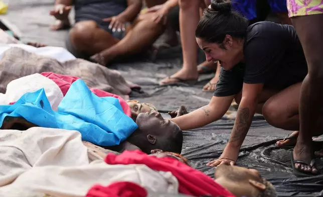EDS NOTE: GRAPHIC CONTENT - A woman mourns beside the bodies of people killed the day before during a police raid targeting the Comando Vermelho gang at the Complexo da Penha favela in Rio de Janeiro, Brazil, Wednesday, Oct. 29, 2025. (AP Photo/Silvia Izquierdo)