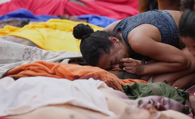 A woman mourns over the bodies of people killed the day before during a police raid targeting the Comando Vermelho gang at the Complexo da Penha favela in Rio de Janeiro, Brazil, Wednesday, Oct. 29, 2025. (AP Photo/Silvia Izquierdo)