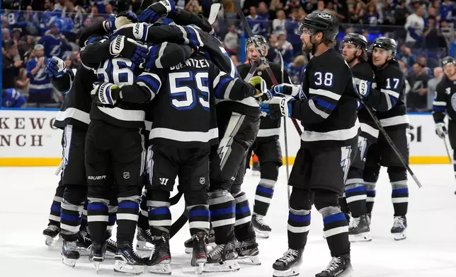 Teammates mob Tampa Bay Lightning right wing Nikita Kucherov (86) after picking up an assist, for his 1,000th career point, on a goal by Brayden Point during the second period of an NHL hockey game against the Anaheim Ducks Saturday, Oct. 25, 2025, in Tampa, Fla. (AP Photo/Chris O'Meara)