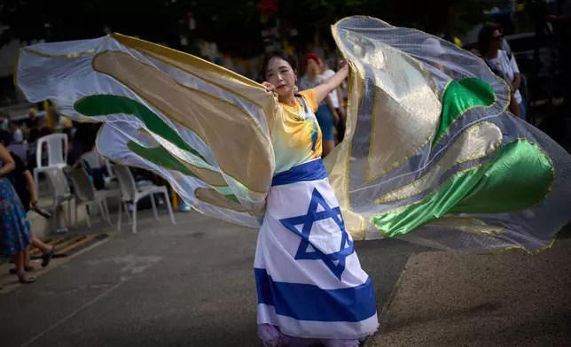 A dancer performs as people gather at a plaza known as hostages square, in Tel Aviv, Israel, Sunday, Oct. 12, 2025. (AP Photo/Emilio Morenatti)