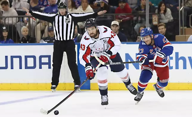 New York Rangers' Adam Fox (23) reaches for the puck behind Washington Capitals' Tom Wilson (43) during the second period of an NHL hockey game, Sunday, Oct. 12, 2025, in New York. (AP Photo/Heather Khalifa)