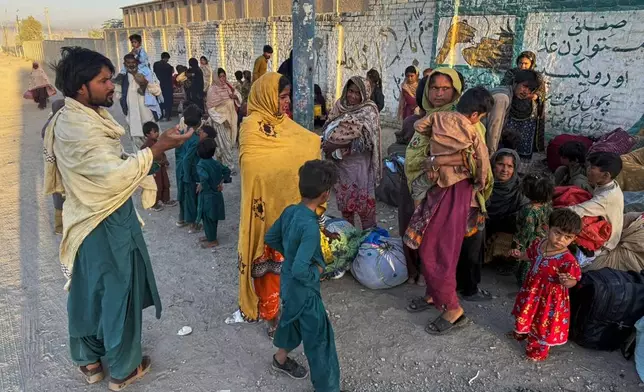 Local residents, who fled their homes following border clashes between Pakistan and Afghan forces, wait for transportation in Chaman, a town on the Pakistan side of the border, Wednesday, Oct. 15, 2025. (AP Photo/H. Achakzai)