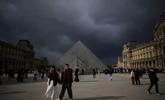 People tour the courtyard of Le Louvre museum Monday, Oct. 27, 2025 in Paris. (AP Photo/Christophe Ena)