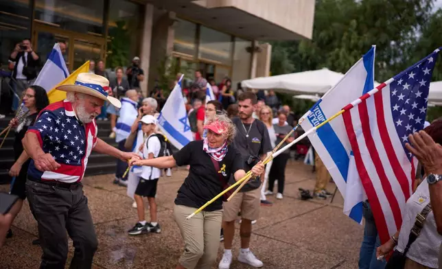 People dance as they celebrate following the announcement that Israel and Hamas have agreed to the first phase of a peace plan to pause the fighting, at a plaza known as hostages square in Tel Aviv, Israel, Thursday, Oct. 9, 2025. (AP Photo/Emilio Morenatti)