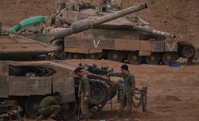 Israeli soldiers work on a tank near the Israeli-Gaza border, as seen from southern Israel, Thursday, Oct. 9, 2025, following the announcement that Israel and Hamas have agreed to the first phase of a peace plan to pause the fighting. (AP Photo/Ariel Schalit)