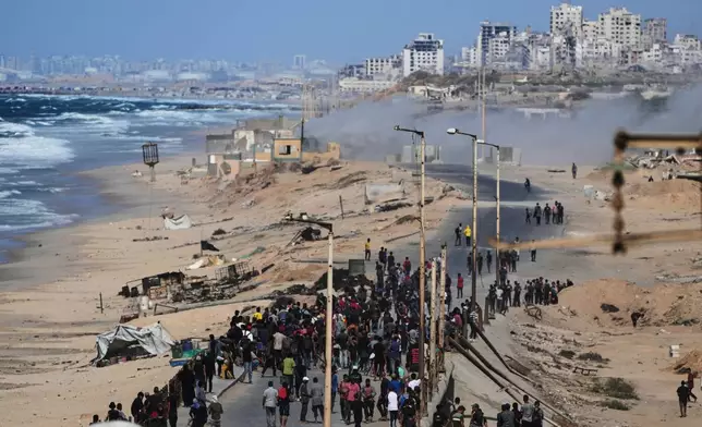 Displaced Palestinians gather on the coastal road near Wadi Gaza after the announcement that Israel and Hamas had agreed to the first phase of a peace plan to pause the fighting, as Israeli tanks block the road leading to Gaza City, in the central Gaza Strip, Thursday, Oct. 9, 2025. (AP Photo/Abdel Kareem Hana)