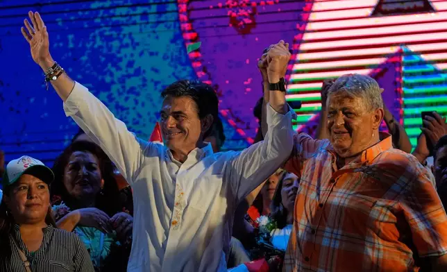 Former Bolivian President Jaime Paz, right, raises the arm of his son, presidential candidate Rodrigo Paz, during a closing campaign rally ahead of the upcoming runoff election in Tarija, Bolivia, Wednesday, Oct. 15, 2025.. (AP Photo/Juan Karita)