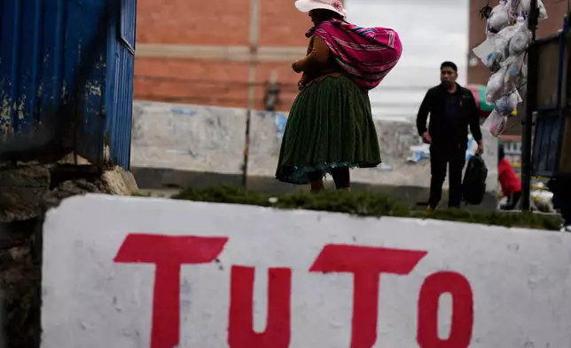 A woman walks past a mural promoting presidential candidate Jorge "Tuto" Quiroga ahead of the runoff election, in El Alto, Bolivia, Thursday, Oct. 16, 2025. (AP Photo/Natacha Pisarenko)