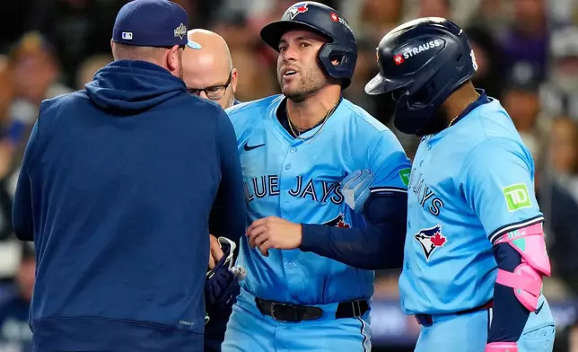 Teammates and staff help Toronto Blue Jays outfielder George Springer (4) off the field after he took a pitch to the knee from Seattle Mariners pitcher Bryan Woo (22) during seventh inning MLB Game 5 of baseball's American League Championship Series action in Seattle, Friday, Oct. 17, 2025. (Frank Gunn/The Canadian Press via AP)