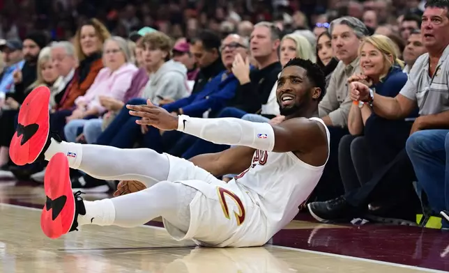 Cleveland Cavaliers guard Donovan Mitchell slides on the floor after being fouled on an attempted 3-point basket in the first half of an NBA basketball game against the Milwaukee Bucks, Sunday, Oct. 26, 2025, in Cleveland. (AP Photo/David Dermer)