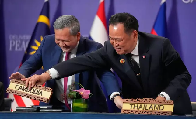 Cambodian Prime Minister Hun Manet, left and Thailand's Prime Minister Anutin Charnvirakul react as they switch country signs during a signing ceremony on the sidelines of the ASEAN Summit in Kuala Lumpur, Malaysia, Sunday, Oct. 26, 2025. (AP Photo/Mark Schiefelbein)