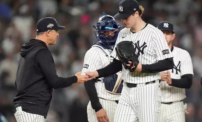 New York Yankees pitcher Cam Schlittler hands the ball to manager Aaron Boone as he leaves the game during the seventh inning of Game 4 of baseball's American League Division Series against the Toronto Blue Jays, Wednesday, Oct. 8, 2025, in New York. (AP Photo/Frank Franklin II)