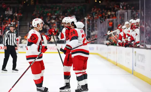 Carolina Hurricanes players embrace Carolina Hurricanes center Seth Jarvis (24) after scoring during the second period of an NHL hockey game Thursday, Oct. 16, 2025, in Anaheim, Calif. (AP Photo/Ethan Swope)