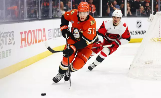 Anaheim Ducks defenseman Olen Zellweger (51) controls the puck against Carolina Hurricanes center Seth Jarvis (24) during the second period of an NHL hockey game Thursday, Oct. 16, 2025, in Anaheim, Calif. (AP Photo/Ethan Swope)