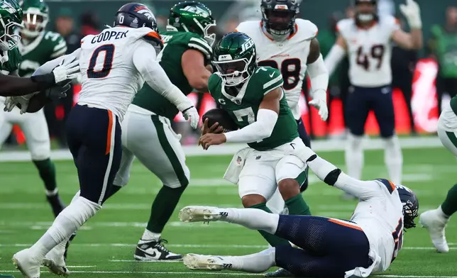 New York Jets quarterback Justin Fields, center, is sacked by Denver Broncos linebackers Jonathon Cooper, left, and Alex Singleton in the second half of an NFL football game Sunday, Oct. 12, 2025, in London. (AP Photo/Ian Walton)