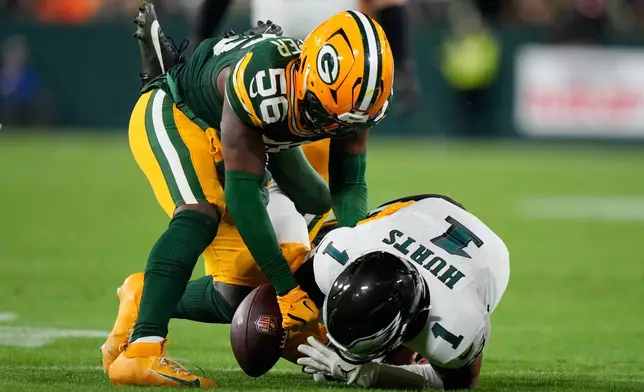 Green Bay Packers linebacker Edgerrin Cooper, left, and Green Bay Packers safety Xavier McKinney (29) tackle Philadelphia Eagles quarterback Jalen Hurts (1) as he fumbles during the first half of an NFL football game Monday, Nov. 10, 2025, in Green Bay, Wis. (AP Photo/Morry Gash)
