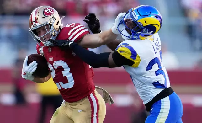 San Francisco 49ers running back Christian McCaffrey, left, runs against Los Angeles Rams safety Quentin Lake during the first half of an NFL football game in Santa Clara, Calif., Sunday, Nov. 9, 2025. (AP Photo/Godofredo A. Vásquez)