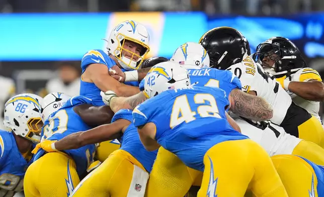 Los Angeles Chargers quarterback Justin Herbert, top left, is stopped by Pittsburgh Steelers players during the first half of an NFL football game Sunday, Nov. 9, 2025, in Inglewood, Calif. (AP Photo/Marcio Jose Sanchez)