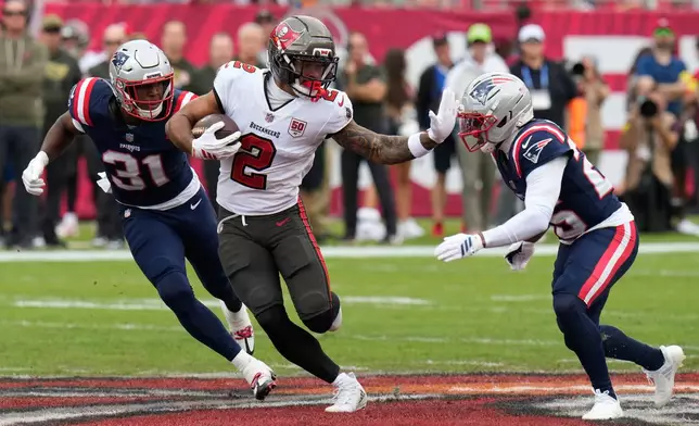 Tampa Bay Buccaneers wide receiver Emeka Egbuka (2) runs after a catch against New England Patriots cornerback Marcus Jones, right, during the first half of an NFL football game Sunday, Nov. 9, 2025, in Tampa, Fla. (AP Photo/Chris O'Meara)