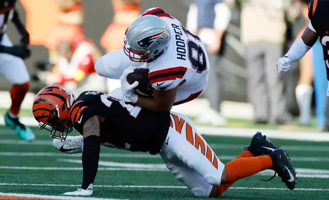 New England Patriots tight end Austin Hooper (81) is tackled by Cincinnati Bengals safety Geno Stone (22) after catching a pass during the first half of an NFL football game, Sunday, Nov. 23, 2025, in Cincinnati. (AP Photo/Jay LaPrete)