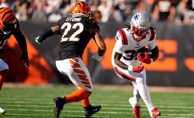 New England Patriots running back Rhamondre Stevenson runs from Cincinnati Bengals safety Geno Stone (22) during the first half of an NFL football game, Sunday, Nov. 23, 2025, in Cincinnati. (AP Photo/Carolyn Kaster)