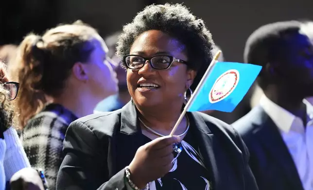 A woman waves the state flag of Virginia at an election night watch party for Virginia Democratic gubernatorial candidate Abigail Spanberger, Tuesday, Nov. 4, 2025, in Richmond, Va. (AP Photo/Stephanie Scarbrough)