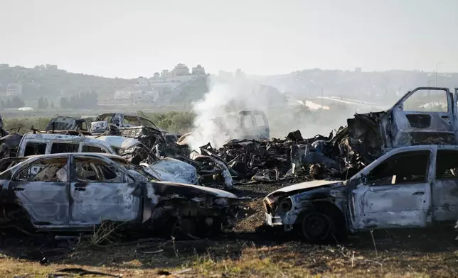 Smoke rises from scorched cars in a scrapyard that was set ablaze the night before by who local residents alleged were Israeli settlers in the town of Huwara near the West Bank city of Nablus, Friday, Nov. 21, 2025. (AP Photo/Nasser Nasser)