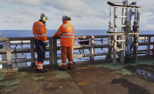 Workers stand at the platform's railing on the INEOS Energy's Siri platform in the North Sea, Denmark, Tuesday, Nov. 25, 2025. (AP Photo/James Brooks)