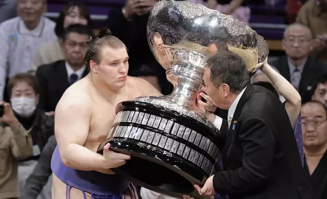 Ukrainian Aonishiki, left, receives a trophy after winning the Kyushu Grand Sumo Tournament in Fukuoka, western Japan, Sunday, Nov. 23, 2025. (Kyodo News via AP)