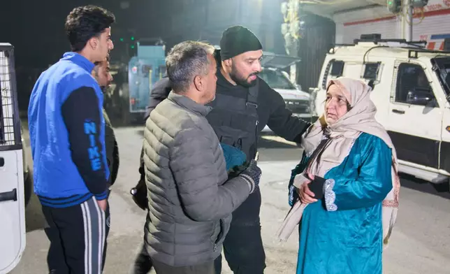 A police officer, standing center and wearing black, talks to relatives of injured colleagues near the site of an explosion inside a police station in Srinagar, Indian controlled Kashmir, Friday, Nov. 14, 2025. (AP Photo/Yasin Dar)