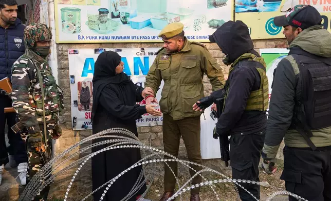 A veiled Kashmiri woman is stopped by an Indian police officer before being allowed to pass a temporary checkpoint near the site of an explosion inside a police station in Srinagar, Indian controlled Kashmir, Saturday, Nov. 15, 2025. (AP Photo/Dar Yasin)
