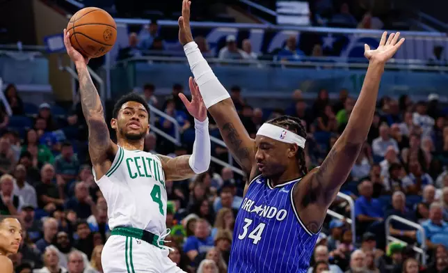 Boston Celtics guard Anfernee Simons (4) shoots two as he is fouled by Orlando Magic center Wendell Carter Jr. (34) during the first half of an NBA basketball game, Sunday, Nov. 9, 2025, in Orlando, Fla. (AP Photo/Kevin Kolczynski)