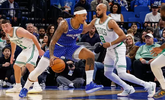 Orlando Magic forward Paolo Banchero, left,is defended by Boston Celtics guard Derrick White (9) during the first half of an NBA basketball game, Sunday, Nov. 9, 2025, in Orlando, Fla. (AP Photo/Kevin Kolczynski)