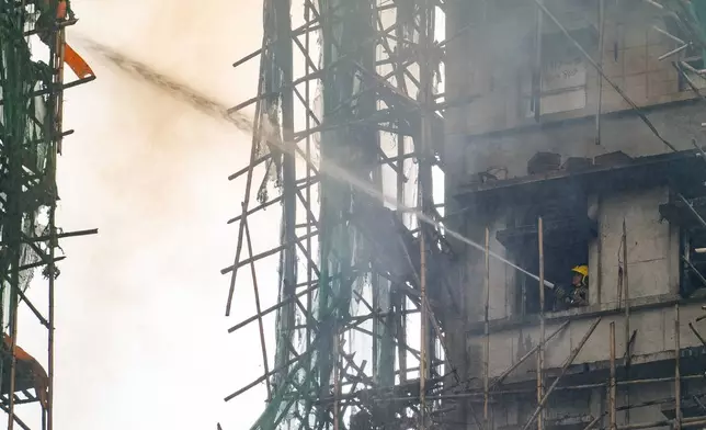 A firefighter works to extinguish a fire that broke out at Wang Fuk Court, a residential estate in the Tai Po district of Hong Kong's New Territories, Thursday, Nov. 27 2025. (AP Photo/Chan Long Hei)