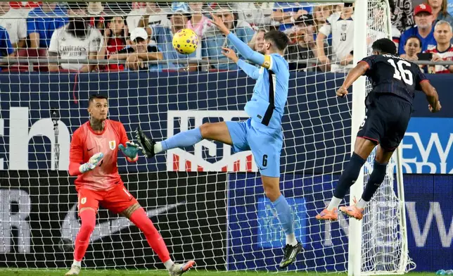 United States' Alex Freeman (16) scores on Uruguay goalie Cristopher Fiermarin (1) as Rodrigo Bentancur (6) defends during the first half of an international friendly soccer game Tuesday, Nov. 18, 2025, in Tampa, Fla. (AP Photo/Jason Behnken)