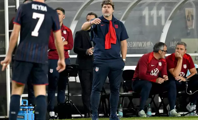 United States head coach Mauricio Pochettino, center, talks to Gil Reyna (7) during the second half of an international friendly soccer game against Uruguay Tuesday, Nov. 18, 2025, in Tampa, Fla. (AP Photo/Jason Behnken)