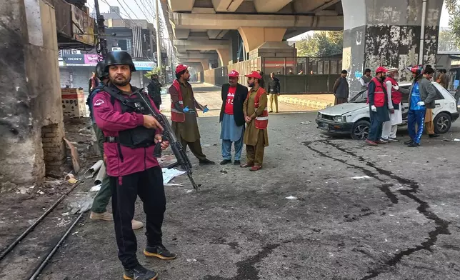 Security officials and rescue workers gather at the site of a suicide bombing at the main gate of headquarters of the Federal Constabulary (FC) in Peshawar, Pakistan, Monday, Nov. 24, 2025. (AP Photo/Muhammad Zubair)