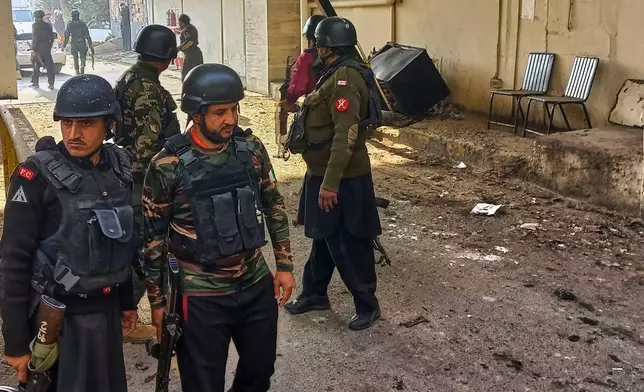 Security officials gather at the site of a suicide bombing at the main gate of headquarters of the Federal Constabulary (FC), in Peshawar, Pakistan, Monday, Nov. 24, 2025. (AP Photo/Muhammad Zubair)