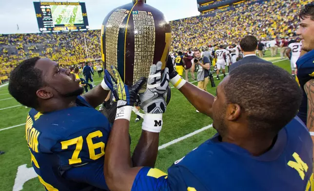 FILE - Michigan defensive tackle Quinton Washington (76) and cornerback Courtney Avery (11) celebrate with the Little Brown Jug trophy after the team's win over Minnesota in an NCAA college football game Oct. 5, 2013, in Ann Arbor, Mich. (AP Photo/Tony Ding, File)