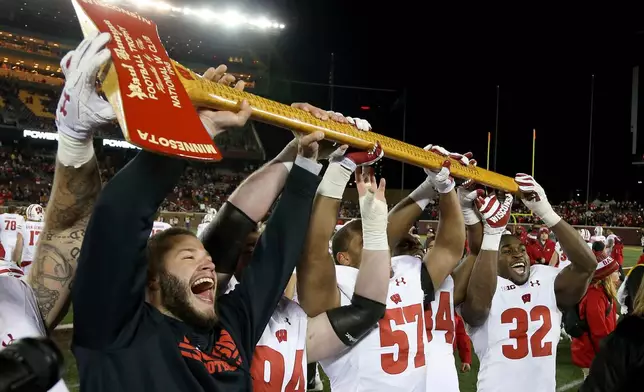 FILE - FILE - In this Nov. 25, 2017, file photo, Wisconsin players hold up Paul Bunyan's Axe up after winning 31-0 against Minnesota in an NCAA college football game in Minneapolis. (AP Photo/Stacy Bengs, File)