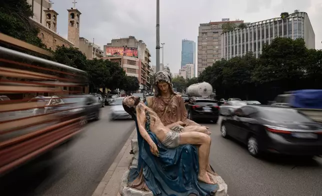 Cars speed past a roadside statue depicting the Virgin Mary holding the body of Jesus, in Beirut, Lebanon, Thursday, Nov. 13, 2025. (AP Photo/Hassan Ammar)
