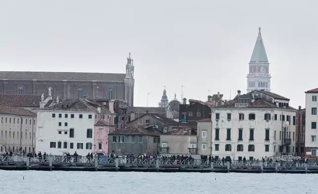 Mourners walk on the 'Votif' Bridge, a 407m temporary floating bridge connecting the city to the cemetery on the island of San Michele, to pay respects to their dead on All Soul's Day, in Venice, Italy, Sunday, Nov. 2, 2025. (AP Photo/Luca Bruno)