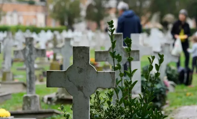 Mourners pay respects to their dead, at the San Michele cemetery, on All Soul's Day, in Venice, Italy, Sunday, Nov. 2, 2025. (AP Photo/Luca Bruno)