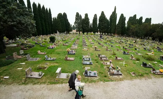 Mourners walk at the San Michele cemetery on the island of San Michele to pay respects to their dead on All Soul's Day, in Venice, Italy, Sunday, Nov. 2, 2025. (AP Photo/Luca Bruno)