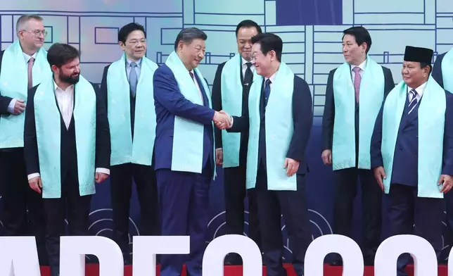 Chinese President Xi Jinping, center left, and South Korean President Lee Jae Myung, center right, shake hands after a group photo at the Asia-Pacific Economic Cooperation (APEC) Economic Leaders' Meeting in Gyeongju, South Korea, Saturday, Nov. 1, 2025. (Yonhap via AP)