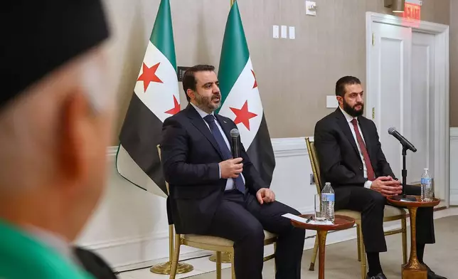 In this photo, released by the Syrian Presidency Press Office, Syrian President Ahmad al-Sharaa, right, listens as Syrian Foreign Minister Asaad al-Shibani, center, speaks during a meeting with representatives of Syrian American organizations in Washington, Saturday, Nov. 8, 2025. (Syrian Presidency Press Office via AP)