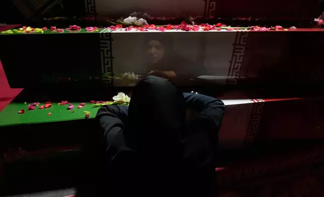 A woman mourns over flag-draped coffins of a group of unknown soldiers who were killed during 1980-88 Iraq-Iran war whose remains were recently recovered from the battlefields, during a ceremony called "Farewell to Martyrs," in Tehran, Iran, Sunday, Nov. 23, 2025. (AP Photo/Vahid Salemi)