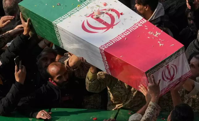 Mourners carry flag-draped coffins of unknown Iranian soldiers killed in the 1980-88 Iraq-Iran war whose remains were recently recovered from the battlefields, during a funeral ceremony in Tehran, Iran, Monday, Nov. 24, 2025. (AP Photo/Vahid Salemi)
