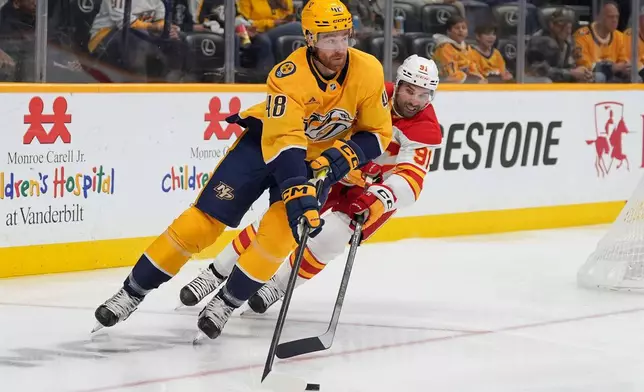 Nashville Predators defenseman Nick Perbix (48) moves the puck against Calgary Flames center Nazem Kadri (91) during the first period of an NHL hockey game Saturday, Nov. 1, 2025, in Nashville, Tenn. (AP Photo/Camden Hall)